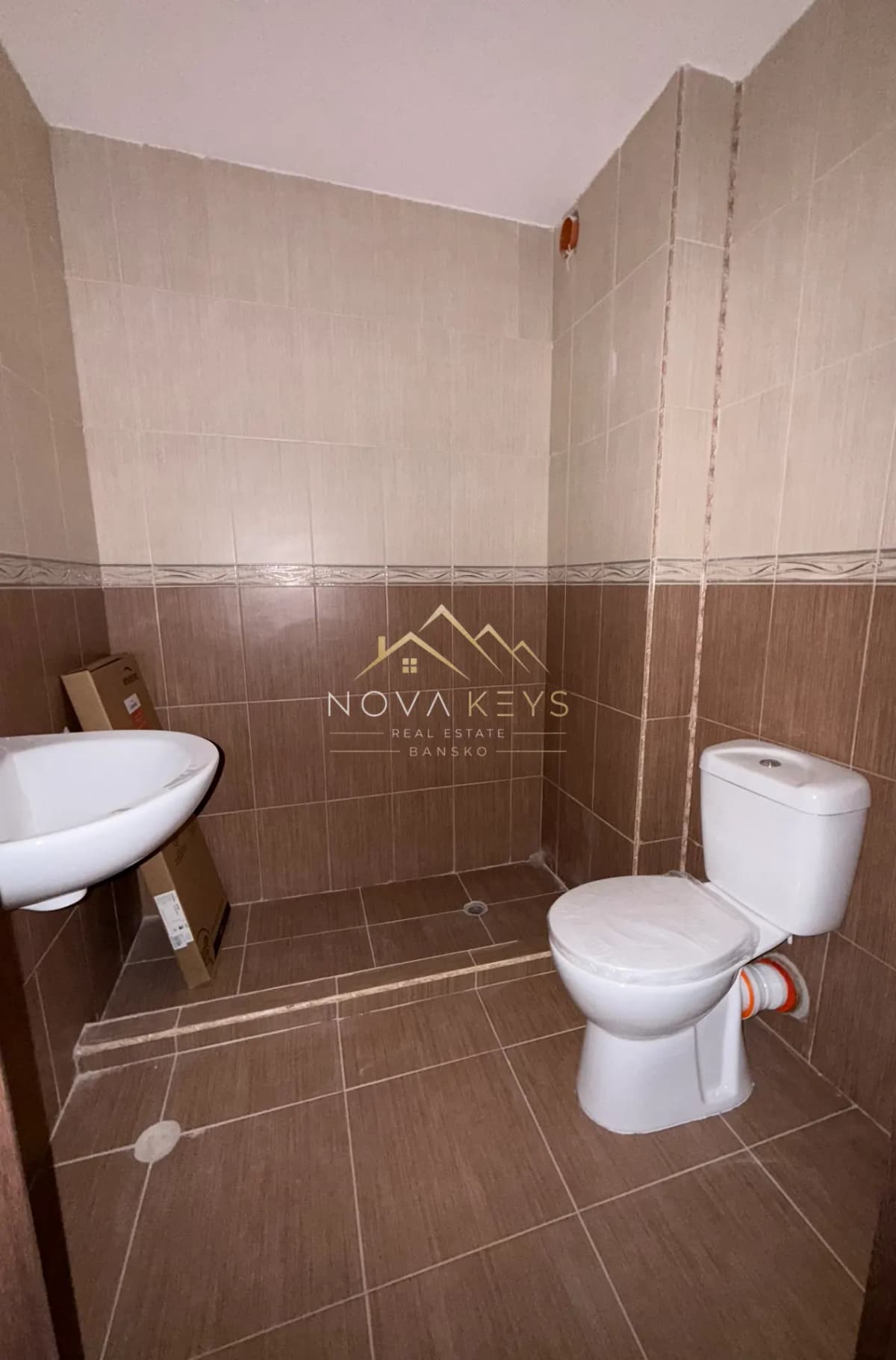 small tiled bathroom with sink and toilet, studio for sale in the Bansko ski area.