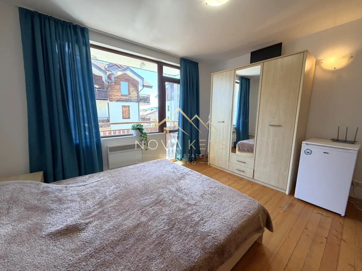 Bedroom with bed, wardrobe, and blue curtains, studio for rent in Bansko.