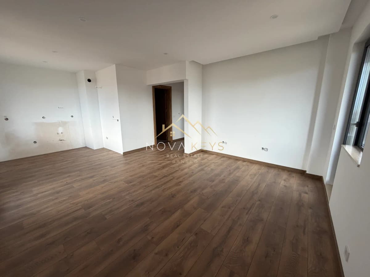 Empty room with wood flooring and window, three-bedroom apartment for sale in the Bansko ski area.