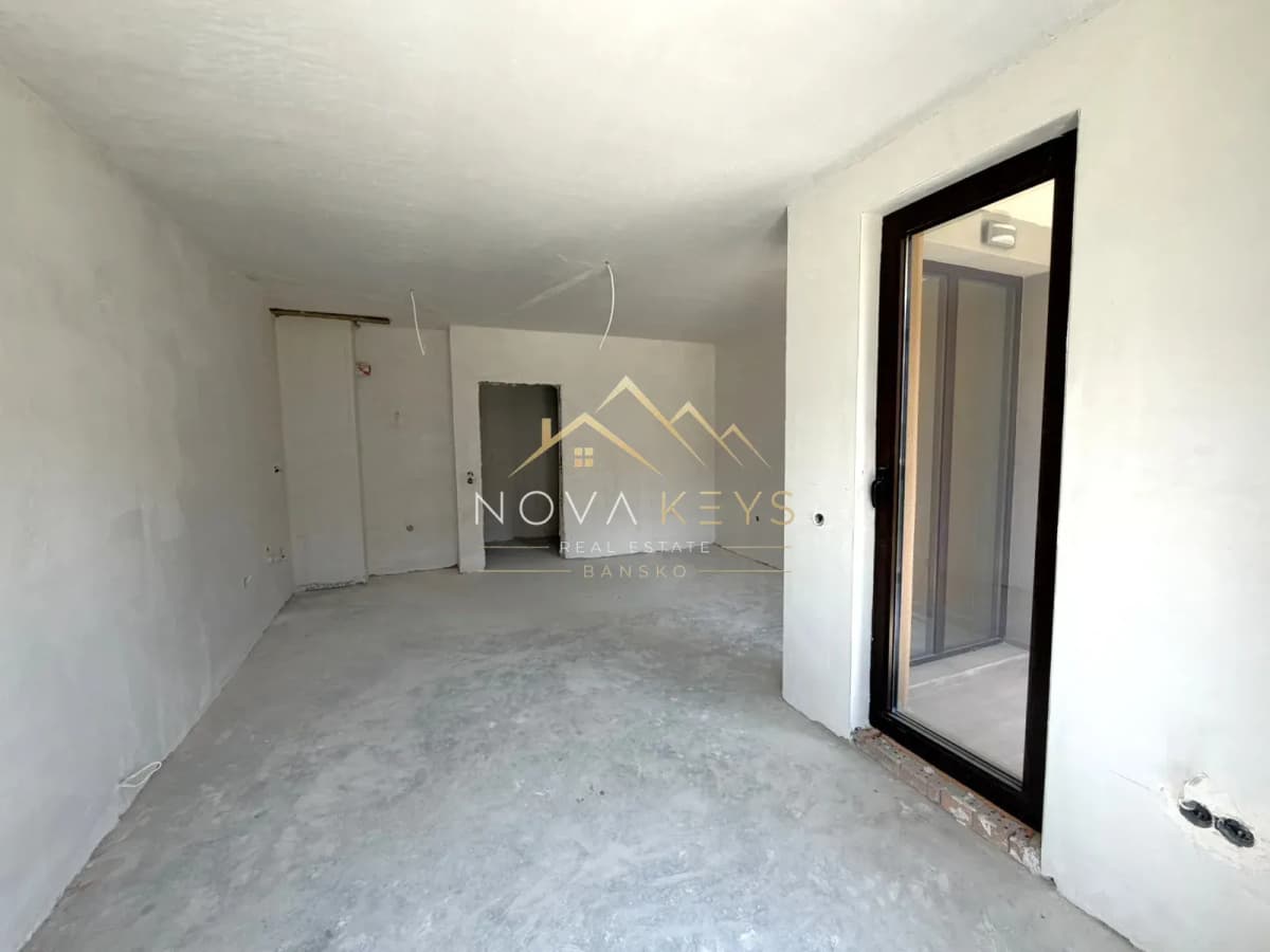 unfinished room with concrete floor and glass door, studio for sale in the Bansko ski area.